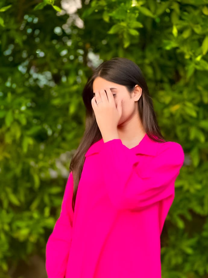 The background is green color and the girl has covered her face with her hands. She looks very beautiful DP